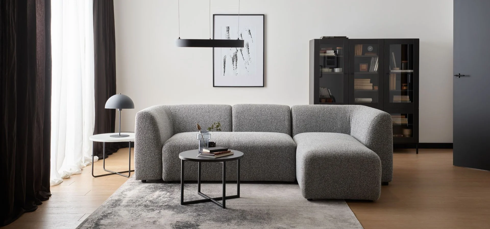 nowoczesny salon z szarą sofą boucle i czarnymi dodatkami